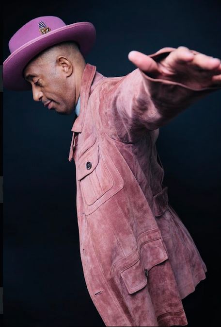 Comedian Sleepy Floyd in dynamic performance pose wearing signature pink suit